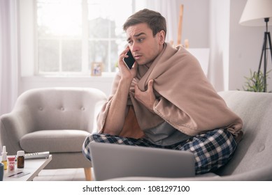 I am sick. Sad young man talking on the phone to his employer while asking about the sick leave - Shutterstock ID 1081297100