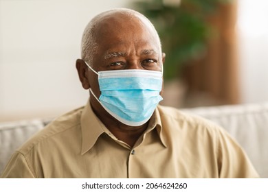 Sick Senior African American Man Wearing Protective Face Mask For Virus Prevention Looking At Camera Sitting Indoors. Covid-19 Protection, Coronavirus Outbreak Concept