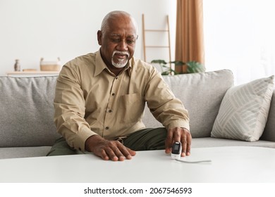 Sick Senior Black Man Measuring Oxygen Saturation Level Using Pulse Oximeter Sitting On Couch At Home. Covid-19, Pulseoxymetry, Medical Device For Ox Measurement Concept