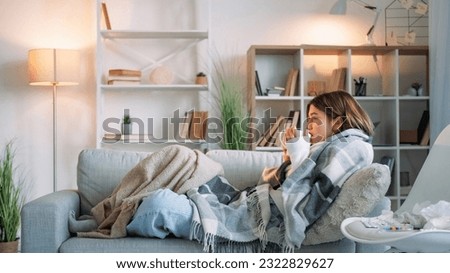 Sick tea. Virus drinking. Sore throat. Shivering woman catching cold suffering influenza holding cup healing grippe sitting wrapped blanket on couch in living room at home.