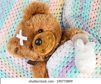 Sick Teddy Bear With Bandage In A Bed