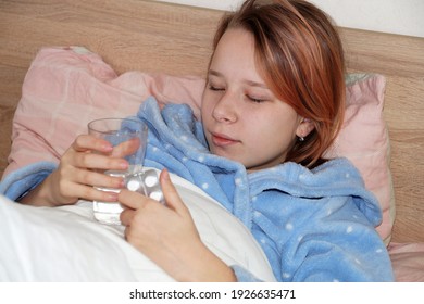 Sick Teenager Girl Taking Medication While Lying In Bed.