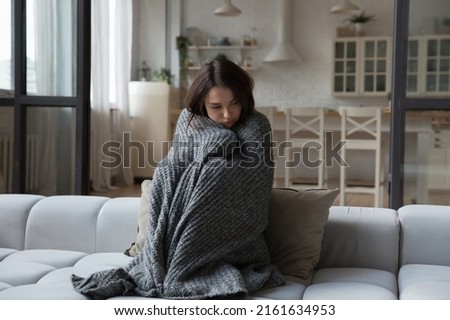 Sick unhappy girl wrapped in warm plaid suffering from cold, fever, high body temperature. Young patient woman feeling unwell, ill due to virus, flu. Healthcare, epidemic concept