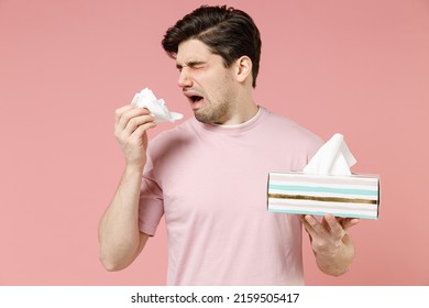 Sick unhealthy ill allergic man has red watery eyes runny stuffy sore nose suffer from allergy trigger symptoms hay fever hold paper napkin handkerchief isolated on pastel pink color background studio - Shutterstock ID 2159505417