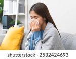 Sick in winter season common cold disease concept, Young woman have a runny nose and flu using tissue to blow her nose on the sofa during winter.