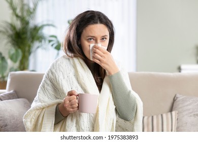 Sick woman blowing her nose, she covered with blanket - Shutterstock ID 1975383893