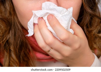 A Sick Woman Blows Her Nose In A Napkin, A Runny Nose. Adult Ill Woman With A Red Scarf, Female Aged 35 Years