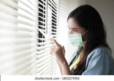 Sick woman of corona virus looking through the window and wearing mask protection and recovery from the illness in home as self quarantine to prevent infection - Powered by Shutterstock