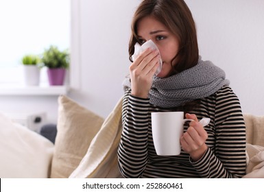 Sick Woman Covered With Blanket Holding Cup Of Tea Sitting On Sofa Couch