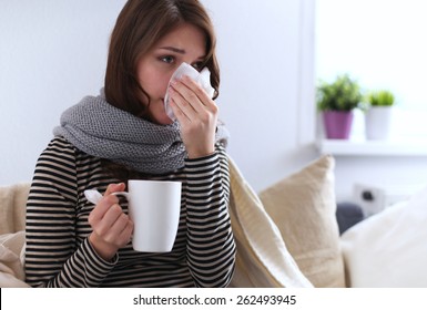 Sick Woman Covered With Blanket Holding Cup Of Tea Sitting On Sofa Couch