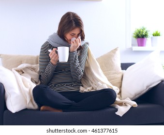 Sick Woman Covered With Blanket Holding Cup Of Tea Sitting On Sofa Couch