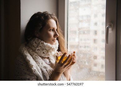 Sick Woman With A Cup Of Tea Sitting By The Window.