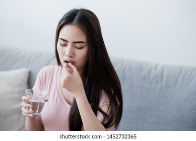 Sick Woman Eating Pills With A Glass Of Water In Hand.
