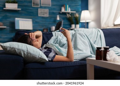 Sick woman with fever, cold and flu measuring temperature with thermometer at home. Young adult with disease feeling unwell taking medicine against headache illness pain, sore throat - Powered by Shutterstock