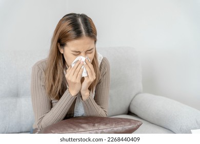 sick woman with a headache and feeling cold on sofa, female sneezing and runny nose with seasonal influenza, allergic, high fever and influenza, resting, virus, coronavirus, feel illness, respiratory - Shutterstock ID 2268440409