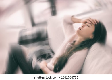 Sick woman with headache feeling faint vertigo holding head in pain with fever and migraine. Blurry motion blur background.