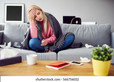 Sick woman with headache sitting under the blanket