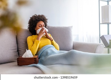 The sick woman, holding a handkerchief, sneezing and feeling freezing, lying on the bed, at home. Health problem. Sick African American woman lying on the sofa - Powered by Shutterstock