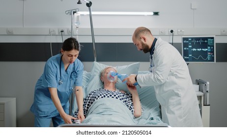 Sick Woman Hyperventilating And Asking About Medical Assistance While Doctor And Nurse Rushing To Help With Respiratory Problem. Specialists Using Oxygen Tube And Oximeter For Patient