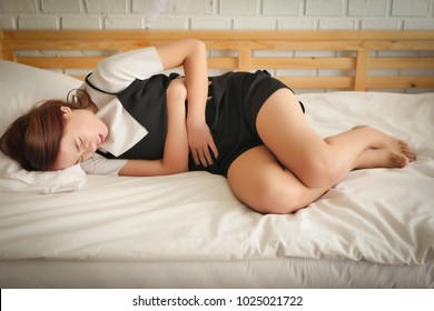 sick woman lying down with menstruation pain, ill woman suffers cramp, stomach ache, belly pain, hand holding belly; woman menstrual pain, period cramp, stomachache, gastritis, reflux pain concept