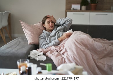 Sick Woman Lying Down Under The Duvet And Looking At Medicine On The Table 