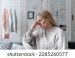 sick woman with nasal pain touching nose and feeling bad, girl with grippe and rhinitis wrapped with warm plaid and sitting upset at home alone