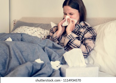 Sick Woman Sneezing In Bed