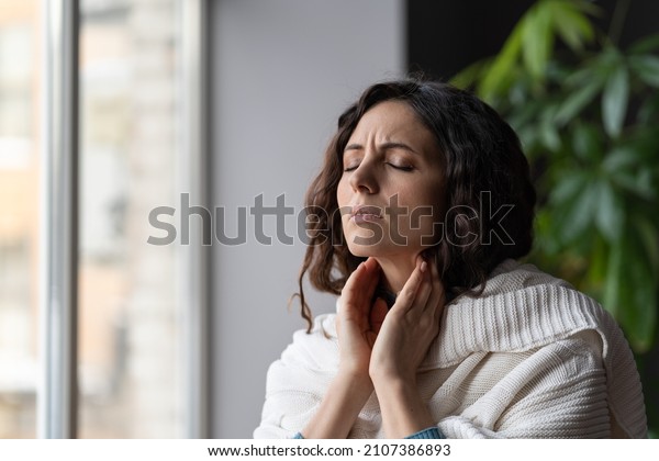 Sick woman suffer from sore throat touch\
enlarged lymph nodes staying home on sick leave. Unhappy young\
female with coronavirus disease, angina or pharyngitis illness\
symptoms. Girl feeling\
discomfort