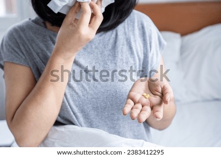 sick woman taking medicine for flu have runny nose and sneezing in bed hand holding tissue paper 