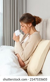 Sick Woman With Tissue Coughing In Bed At Home