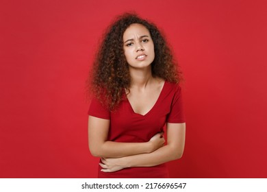 Sick Young African American Woman 20s She In Casual T-shirt Posing Isolated On Red Background Studio Portrait. People Lifestyle Concept. Mock Up Copy Space. Having Abdominal Pain, Put Hands On Stomach