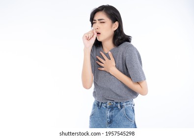 Sick young Asian woman in grey t-shirt and jeans feeling unwell and coughing as symptom for cold or bronchitis. Woman have symptoms of COVID-19. Healthcare concept.