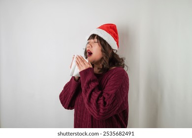 Sick young asian woman wearing santa clause hat and red long sleeved sweater is sneezing and covering using tissue, isolated over white background. Concept for Christmas Holiday and New Year Party - Powered by Shutterstock