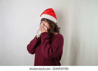 Sick young asian woman wearing santa clause hat and red long sleeved sweater is sneezing and covering using tissue, isolated over white background. Concept for Christmas Holiday and New Year Party - Powered by Shutterstock