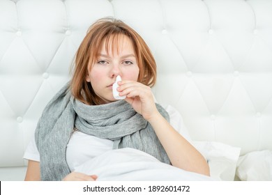 Sick young girl with flu using nose spray at home. Empty space for text