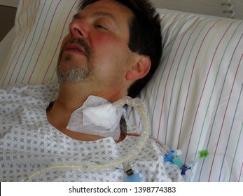 Sick young man lying in a hospital bed with central venous catheter (CVC) administered fluids and parenteral nutrition (PN)