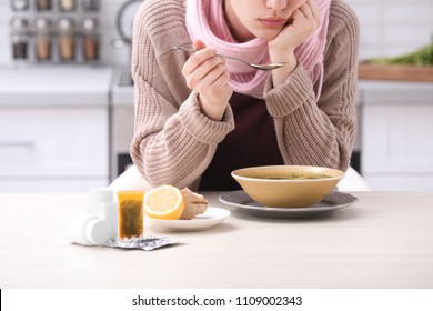 Sick Young Woman Eating Broth To Cure Cold At Table In Kitchen