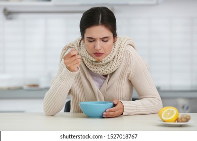 Sick Young Woman Eating Soup To Cure Flu At Table In Kitchen