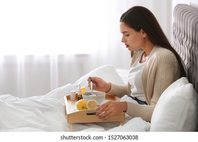 Sick Young Woman Eating Soup To Cure Flu In Bed At Home