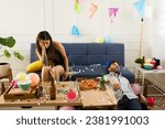 Sick young woman with a headache and nausea looking hangover with an unconscious man after celebrating drinking during a birthday party