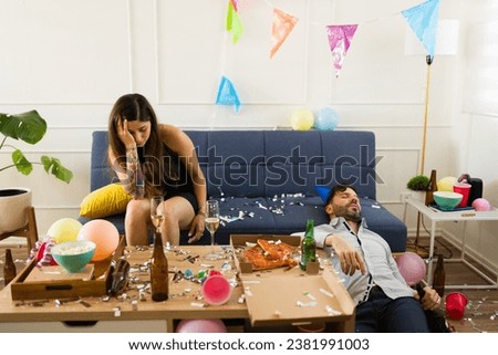 Sick young woman with a headache and nausea looking hangover with an unconscious man after celebrating drinking during a birthday party