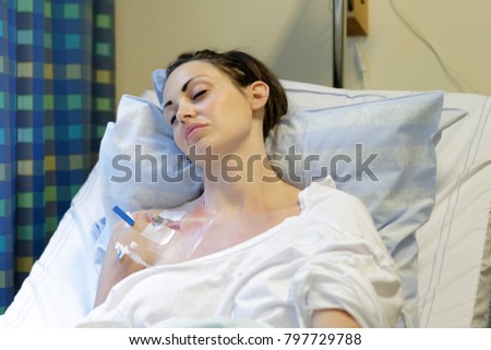Sick young woman laying in hospital bed with Central Venous Catheter (CVC) being administered fluids and Parenteral Nutrition (PN)