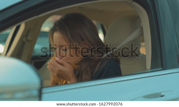 Sick young woman sitting\
in car sneeze holds a handkerchief vehicle influenza health illness\
flu medical sickness problem business infection headache slow\
motion