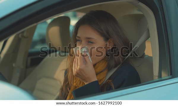 Sick young woman sitting\
in car sneeze holds a handkerchief vehicle influenza health illness\
flu medical sickness problem business infection headache slow\
motion