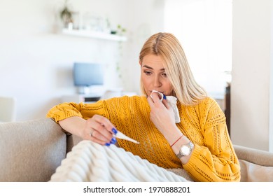 Sickness, covid-19, coronavirus virus problem concept. Woman being sick having flu lying on sofa looking at temperature on thermometer. Sick woman lying in bed with high fever. Cold flu and migraine. - Shutterstock ID 1970888201