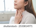 Sickness in inflaming asian young woman, girl use hand check self touch at sore throat, pain thyroid gland on neck or disease reflux, acid of suffer people at home. Medical and healthcare.