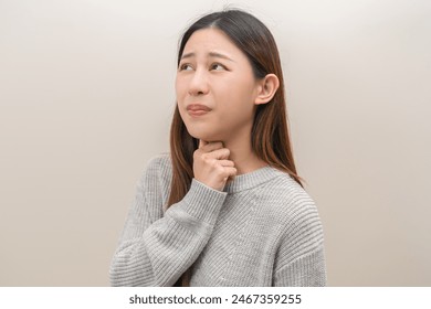 Sickness in inflaming asian young woman, girl use hand check self touch at sore throat, pain thyroid gland on neck or disease reflux, acid of suffer people on wall background. Medical and healthcare. - Powered by Shutterstock