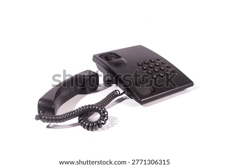 Side angle view of a black office desk phone with its handset off the base, isolated on a white background. Concept of communication and customer service. 
