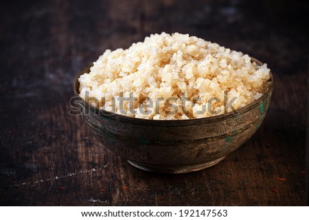 Side angle view of a heaped rustic bowl of healthy cooked quinoa, a pseudo-cereal whose seeds are rich in protein and nutrients and an important ingredient in vegetarian cuisine