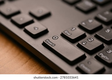 Side Angled Top View Macro Close-Up Black Keyboard Highlighting Zero and Insert Keys on Numeric Keypad with Soft Blurred Tech Backgrounds